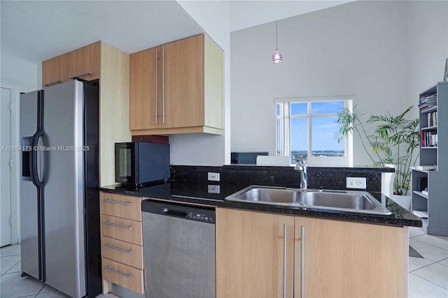 kitchen with hanging light fixtures, stainless steel dishwasher, dark stone counters, light tile patterned flooring, and sink