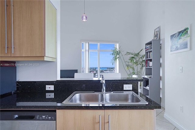 kitchen featuring sink, hanging light fixtures, light tile patterned flooring, stainless steel dishwasher, and dark stone counters