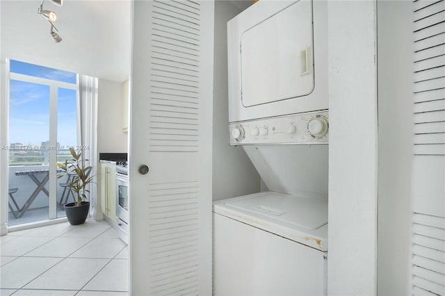 clothes washing area featuring light tile patterned flooring and stacked washer and clothes dryer