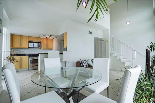 dining space featuring track lighting, light tile patterned floors, and a high ceiling