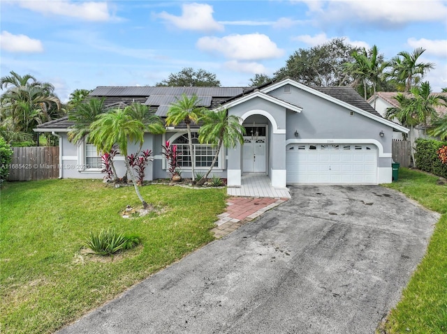 single story home with solar panels, a garage, and a front lawn