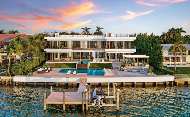 back house at dusk with a water view and a patio