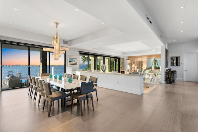 dining space with a water view and a tray ceiling