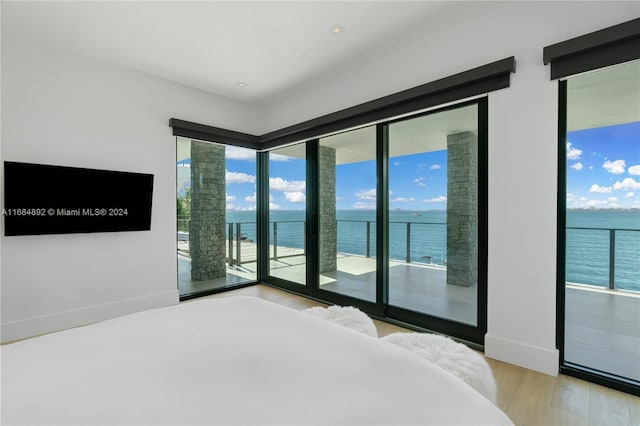 bedroom featuring a water view, light hardwood / wood-style floors, and access to outside