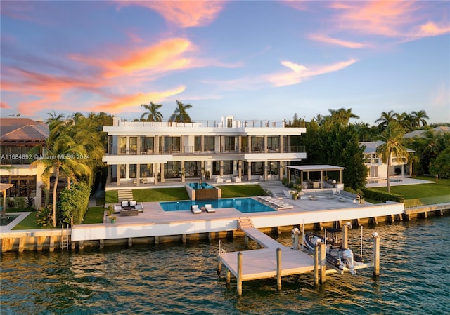 back house at dusk featuring a patio area and a water view