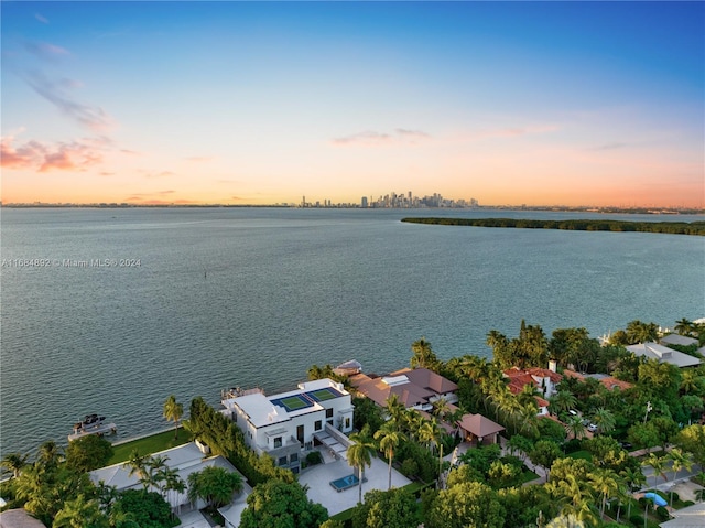 aerial view at dusk featuring a water view