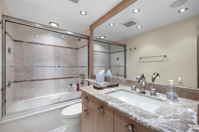 full bathroom featuring toilet, combined bath / shower with glass door, and vanity