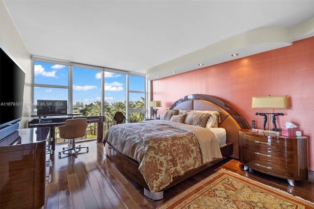 bedroom featuring multiple windows, floor to ceiling windows, and dark hardwood / wood-style flooring