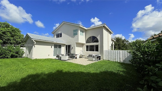 rear view of property featuring outdoor lounge area, a yard, and a patio