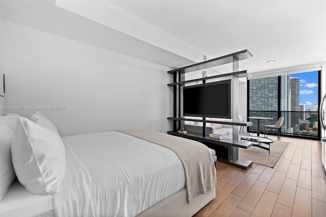 bedroom featuring a wall of windows and hardwood / wood-style floors