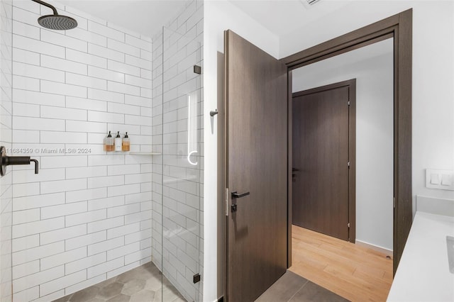 bathroom featuring a tile shower, vanity, and wood-type flooring