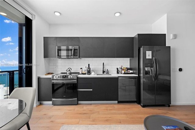 kitchen with light hardwood / wood-style floors, decorative backsplash, stainless steel appliances, and sink