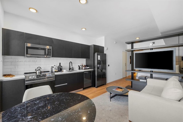 kitchen with sink, appliances with stainless steel finishes, light hardwood / wood-style flooring, and tasteful backsplash