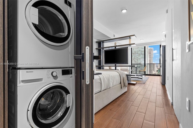 laundry room featuring light hardwood / wood-style floors and stacked washing maching and dryer