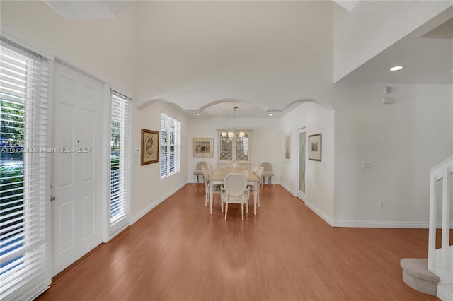 unfurnished dining area featuring hardwood / wood-style floors, a chandelier, and a high ceiling