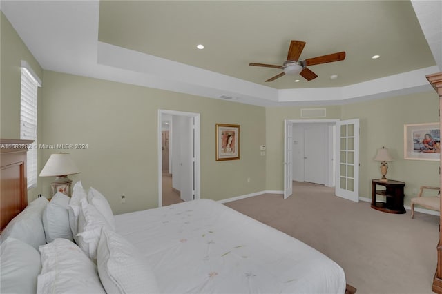 carpeted bedroom with ceiling fan and a tray ceiling