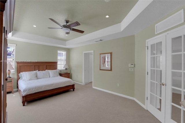 bedroom with a tray ceiling, light carpet, and ceiling fan