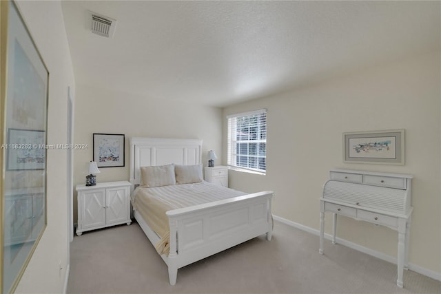 bedroom featuring a textured ceiling and light carpet