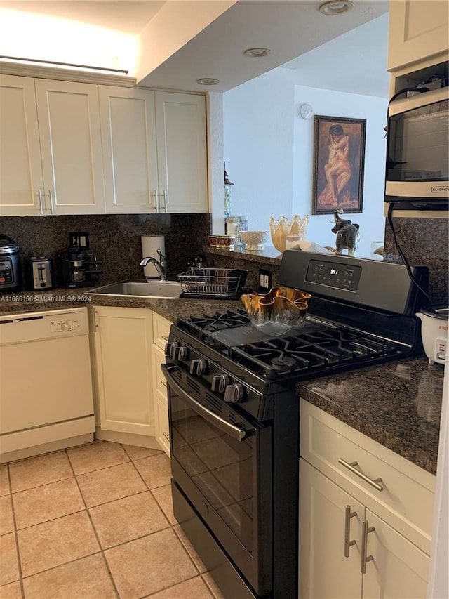 kitchen featuring decorative backsplash, stainless steel appliances, sink, light tile patterned floors, and white cabinets