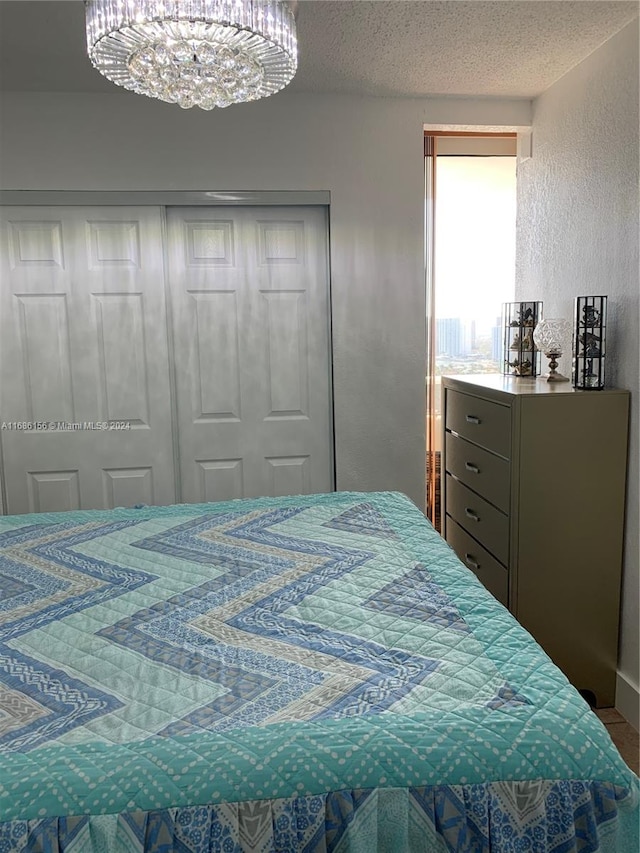 bedroom featuring a notable chandelier, a textured ceiling, and a closet