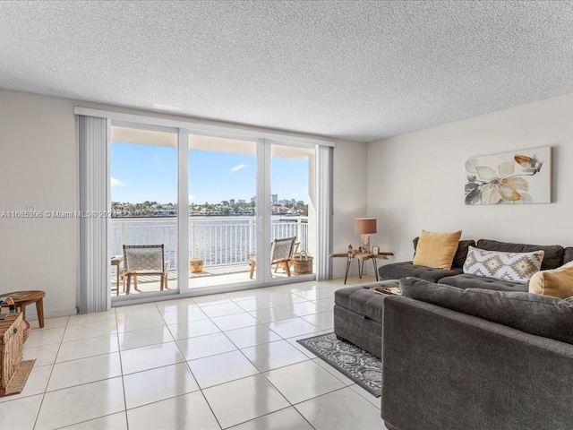 living room featuring light tile patterned floors, a textured ceiling, a water view, and expansive windows