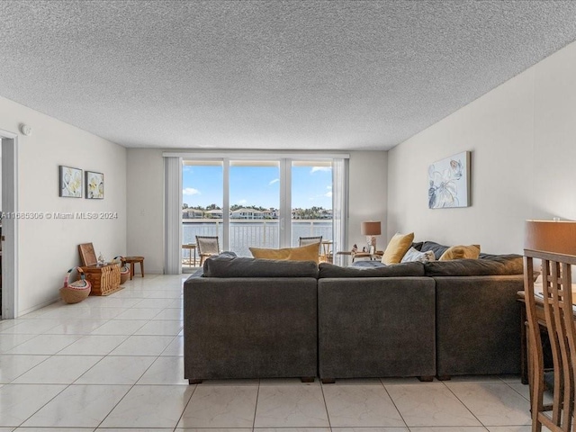 tiled living room with a water view and a textured ceiling