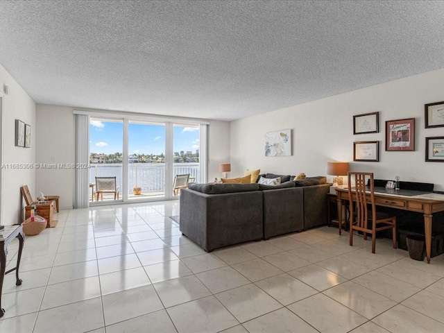 living room featuring floor to ceiling windows, light tile patterned flooring, a water view, and a textured ceiling