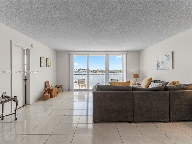 tiled living room featuring a water view, a wall of windows, and a textured ceiling