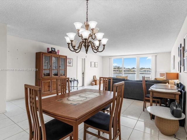 dining area featuring a water view, light tile patterned floors, a textured ceiling, and an inviting chandelier