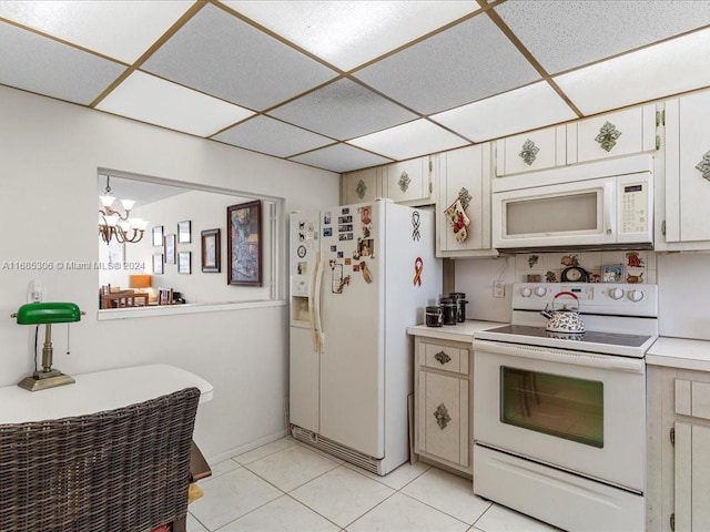 kitchen with white cabinetry, light tile patterned floors, white appliances, and an inviting chandelier