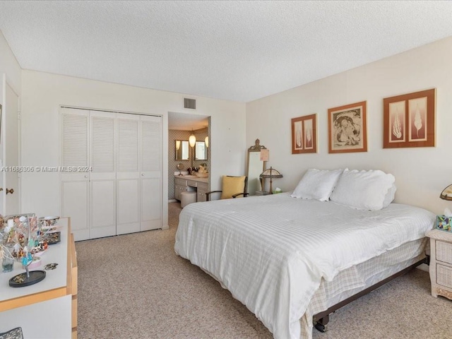 bedroom featuring a textured ceiling, connected bathroom, light colored carpet, and a closet