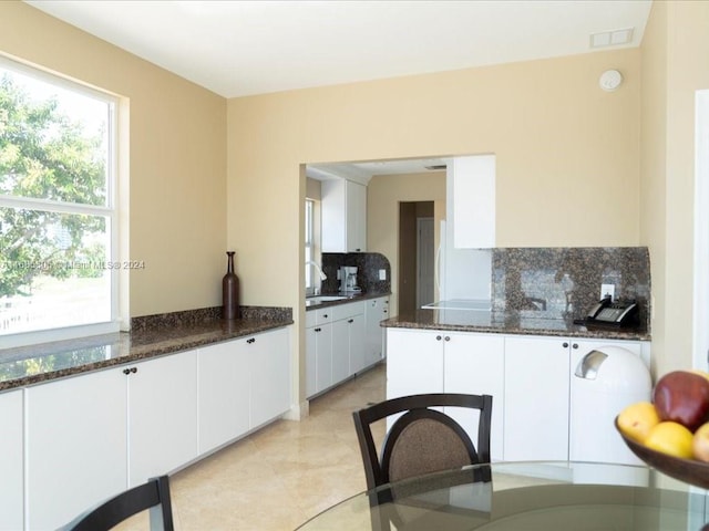 kitchen with backsplash, sink, white cabinets, and dark stone counters