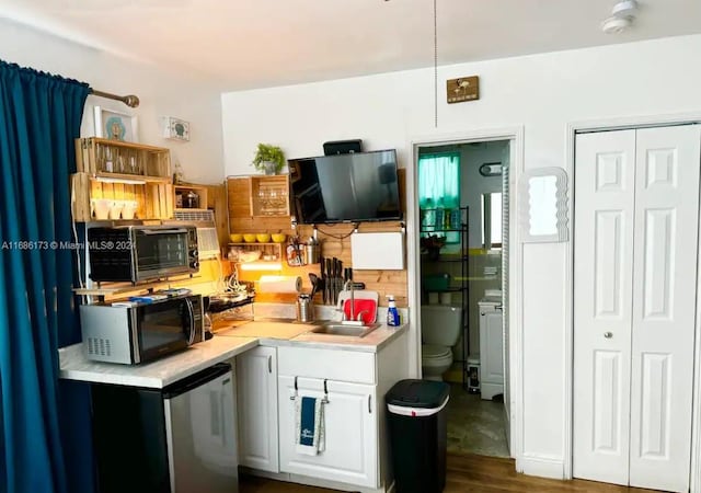 kitchen featuring sink, stainless steel fridge, white cabinetry, and dark hardwood / wood-style floors