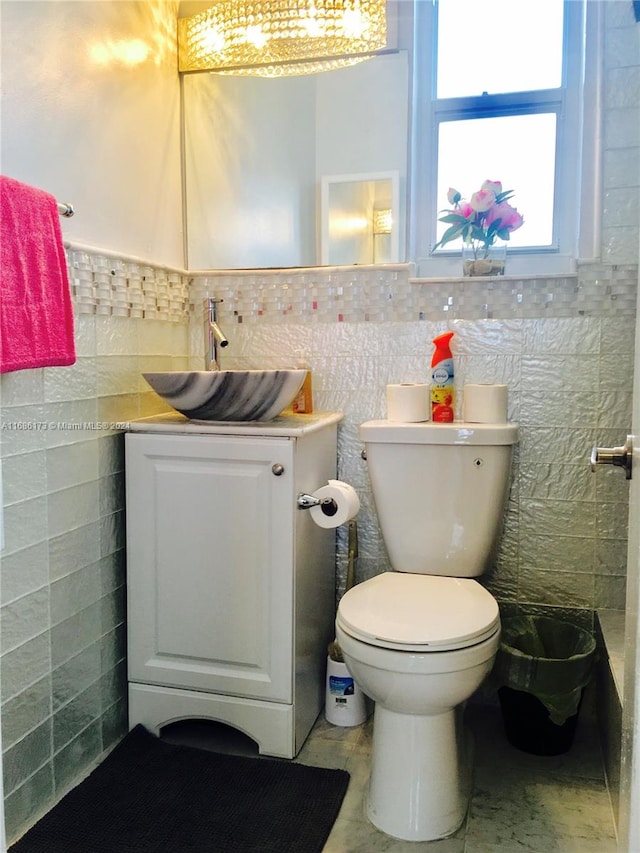 bathroom with vanity, toilet, and tile walls