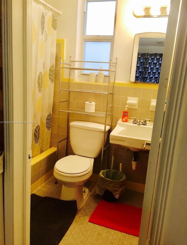 full bathroom featuring toilet, shower / bath combo with shower curtain, sink, and tile walls