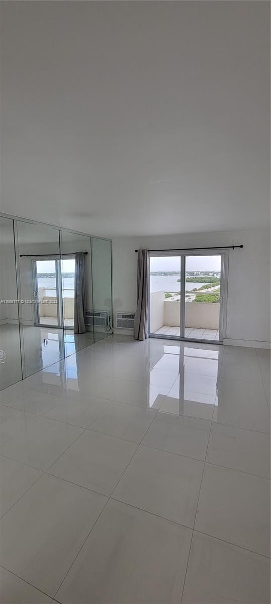 empty room featuring an AC wall unit and light tile patterned floors