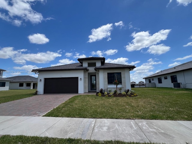 view of front of property with a garage, central air condition unit, and a front lawn