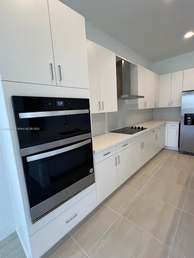 kitchen featuring white cabinetry, light tile patterned flooring, wall chimney range hood, and stainless steel appliances