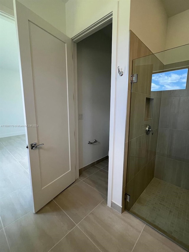 bathroom with tile patterned floors and a shower with door