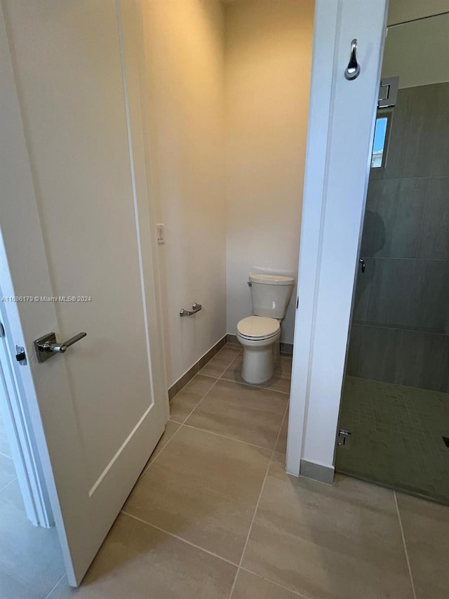 bathroom featuring tile patterned flooring, toilet, and a shower with shower door