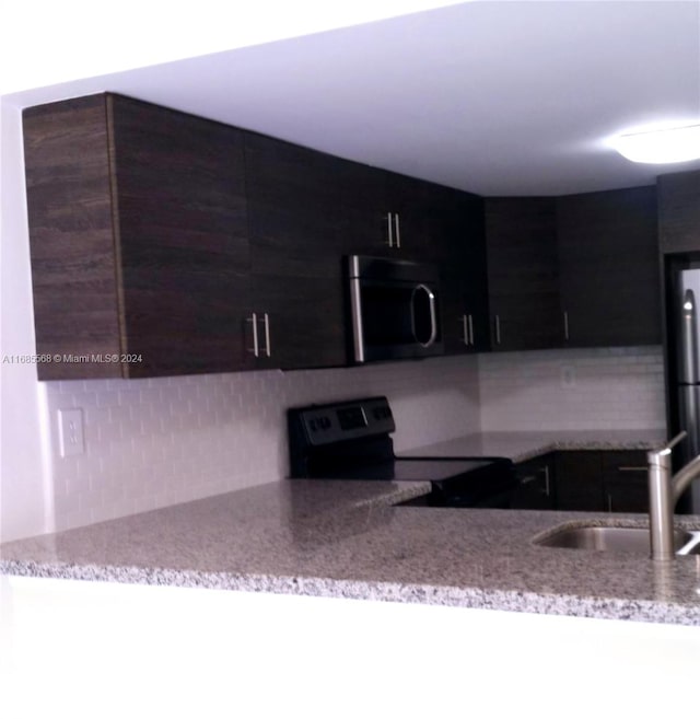 kitchen featuring sink, backsplash, light stone countertops, and electric range