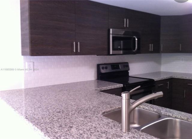 kitchen with appliances with stainless steel finishes, decorative backsplash, light stone countertops, and sink