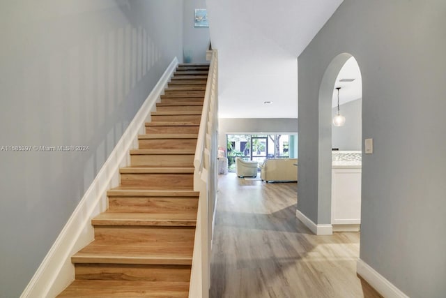 staircase featuring wood-type flooring and lofted ceiling