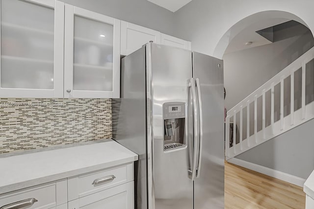 kitchen with backsplash, stainless steel fridge with ice dispenser, white cabinetry, and light hardwood / wood-style floors