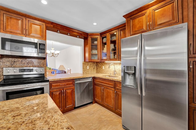 410 SE 2nd St Unit 220, Hallandale Beach, FL 33009 - kitchen with brown cabinets, light stone counters, a sink, appliances with stainless steel finishes, and backsplash
