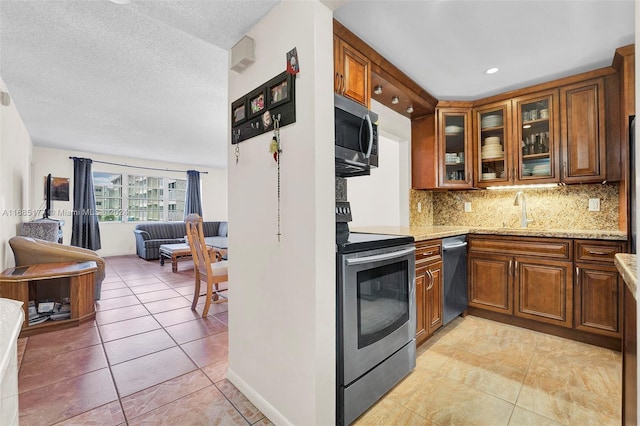 410 SE 2nd St Unit 220, Hallandale Beach, FL 33009 - kitchen with backsplash, appliances with stainless steel finishes, brown cabinets, a sink, and open floor plan
