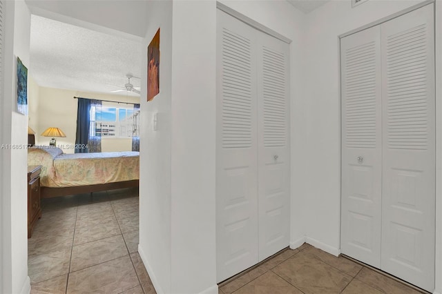 tiled bedroom with multiple closets and a textured ceiling