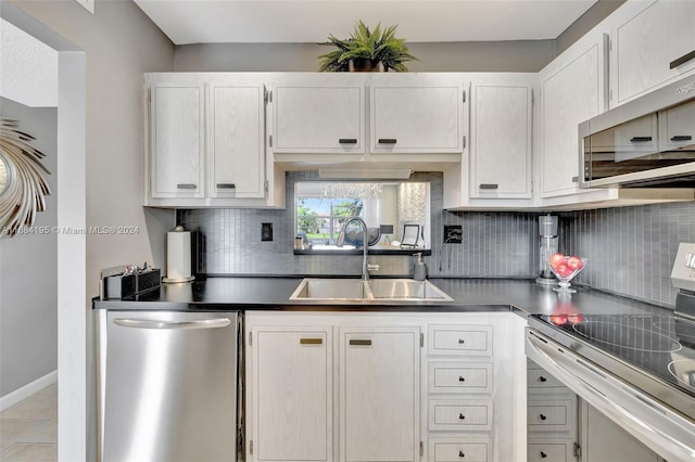 kitchen with backsplash, sink, white cabinets, light tile patterned floors, and appliances with stainless steel finishes