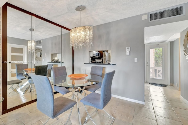 dining space with a textured ceiling, a chandelier, and light tile patterned floors