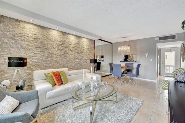 living room featuring a notable chandelier, a textured ceiling, and light tile patterned flooring